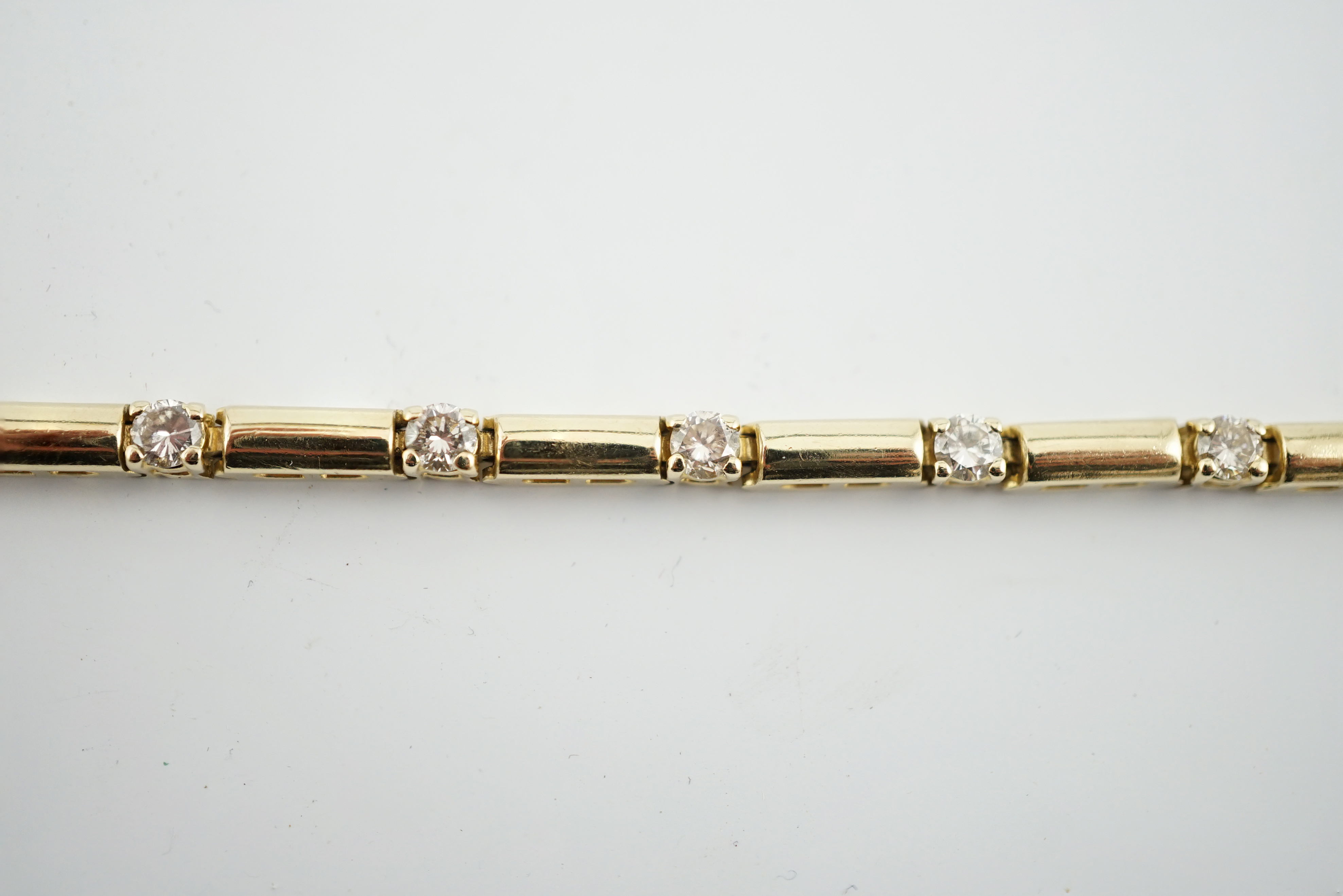 A modern 14k gold and fifteen stone diamond set line bracelet